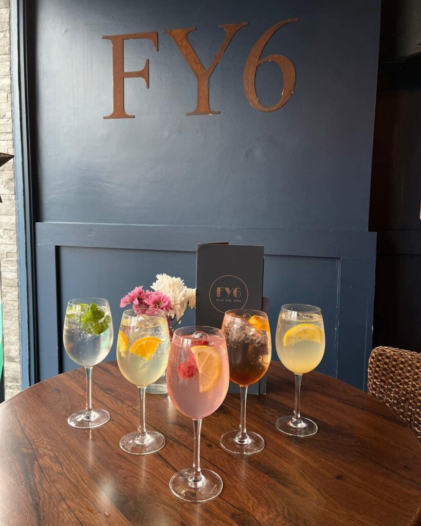 Five cocktails and gin glasses on a table in front of the FY6 sign
